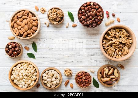 mixed nuts in wooden bowl. Mix of various nuts on colored background. pistachios, cashews, walnuts, hazelnuts, peanuts and brazil nuts. Stock Photo
