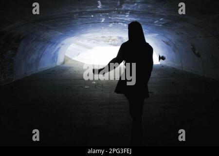 Woman walks alone under a tunnel Stock Photo