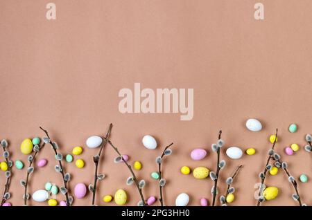 brunch willow and Easter Colorful chocolate eggs on on a beige background. Spring holiday and tradition concept. Flat lay. Happy easter card. Copy spa Stock Photo