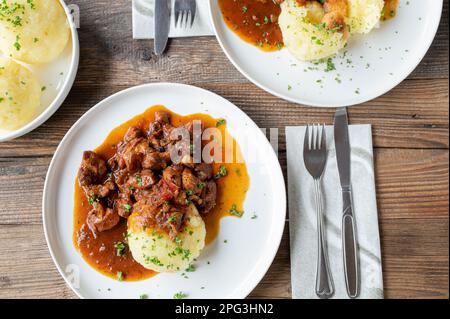 Chicken ragout with potato dumplings on a plate on wooden table Stock Photo