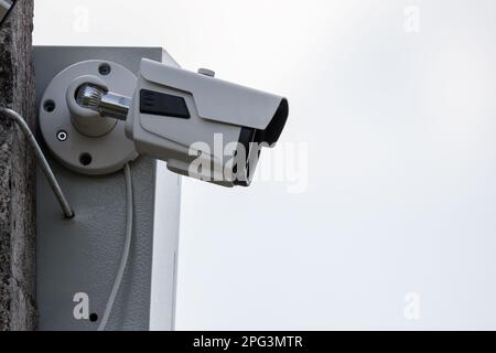 CCTV observation is in progress. Closed-circuit television camera is mounted on concrete street pole under bright sky Stock Photo