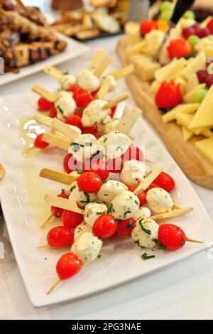 Caprese skewers with tomatoes, mozzarella balls, basil and spices on ...