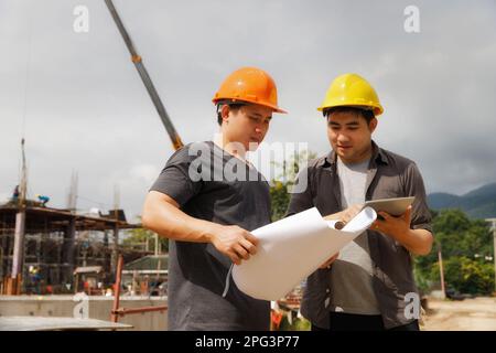 Team of construction workers discussing project details with blueprint in construction site. Stock Photo