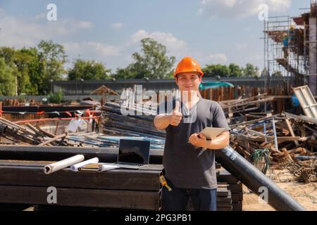 Male Engineer with arms crossed standing at a construction site looking happy. Stock Photo