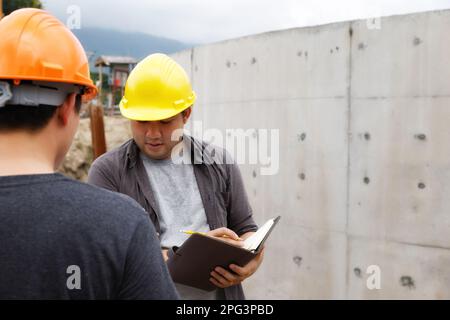 Team of construction workers discussing project details with blueprint in construction site. Stock Photo