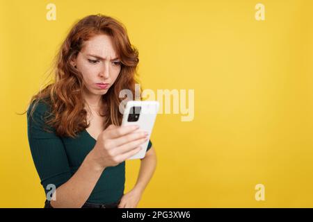 Worried redheaded woman using a mobile phone Stock Photo