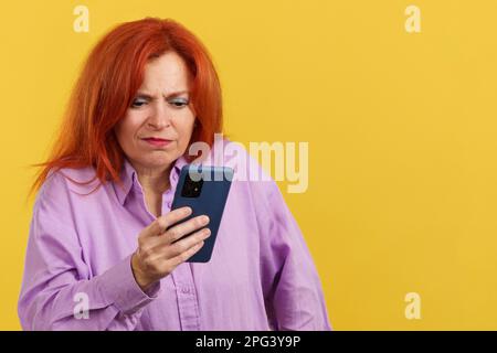 Worried redheaded mature woman using a mobile phone Stock Photo