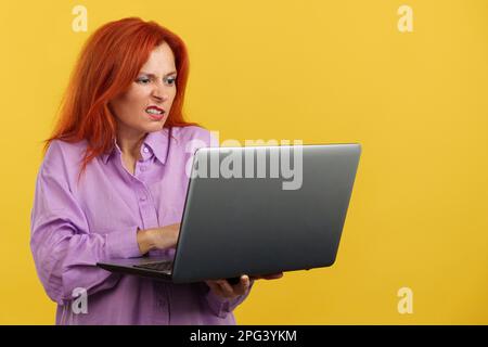 Mature redheaded woman having a problem with a laptop Stock Photo