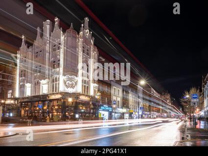 Traffic passes the distinctive Art Nouveau exterior of the Rising Sun pub at night on Tottenham Court Road in central London. Stock Photo
