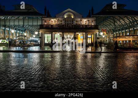 The regenerated covered market hall at Covent Garden is lit at night in central London. Stock Photo