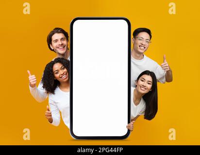 Happy People Peeking Out Behind Big Blank Smartphone And Showing Thumb Up Stock Photo