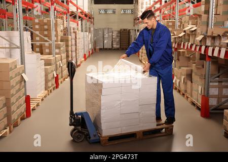 Worker wrapping boxes in stretch film at warehouse Stock Photo