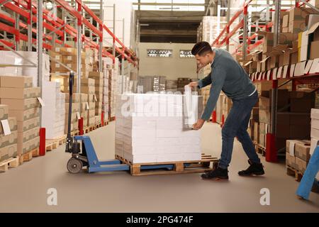 Worker wrapping boxes in stretch film at warehouse Stock Photo