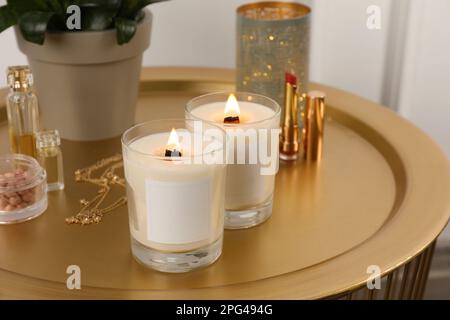 Burning soy candles, cosmetics and stylish accessories on table indoors Stock Photo