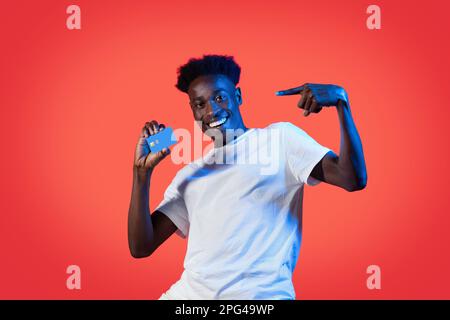 Cheerfful black guy pointing at bank card in his hand Stock Photo