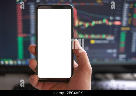 Black phone with blank mockup screen on rising stock graph. Closeup hand showing smartphone isolated white display. Online banking, Fund App use. Fina Stock Photo