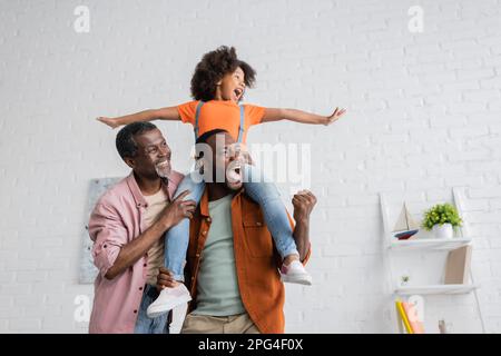 Excited african american man having fun with daughter and dad at home,stock image Stock Photo