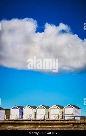 Large white cumulus cloud floating above beach huts Stock Photo