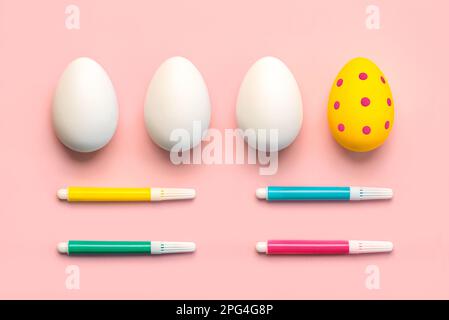 Happy Easter. Colorful easter painted egg and three white easter eggs with colored markers over pink background Stock Photo