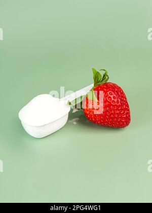 Strawberry protein powder in a measuring cup on green background. Extra supplement for healthy life. Copy space Stock Photo