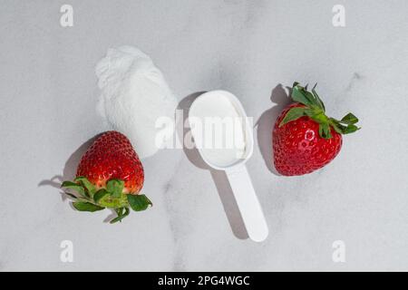 Fresh ripe strawberry with collagen powder or protein in a scoop. Extra protein intake. Natural beauty and health supplement. Plant or fish based. Stock Photo