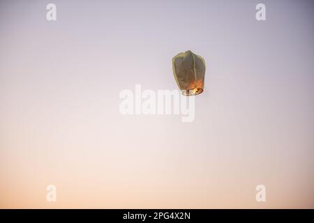 Chinese, paper, yellow lantern in the blue sky at sunset. Making wishes. Earth pollution. Copy space Stock Photo