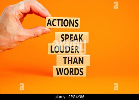 Actions speak louder words symbol. Concept words Actions speak louder than words on wooden blocks. Beautiful orange table orange background. Business Stock Photo