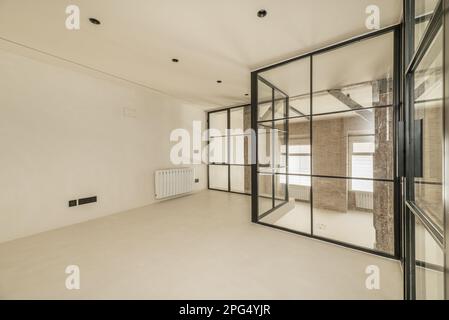 Metal and glass enclosure of a loft with polished white cement walls and floors Stock Photo