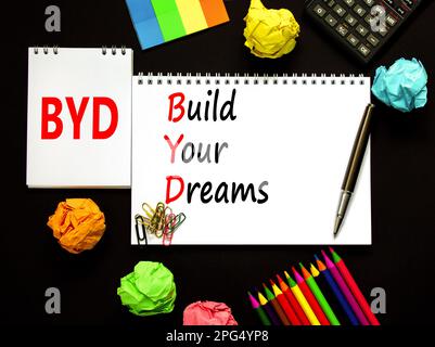 BYD build your dreams symbol. Concept words BYD build your dreams on white note on a beautiful black background. Pencil and pen. Calculator. Business Stock Photo