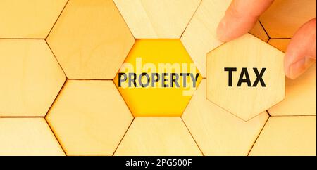 Property tax symbol. Concept words Property tax on wooden puzzles. Beautiful yellow table yellow background. Businessman hand. Business and property t Stock Photo