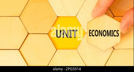 Unit economics symbol. Concept words Unit economics on puzzles. Beautiful yellow table yellow background. Businessman hand. Business and unit economic Stock Photo