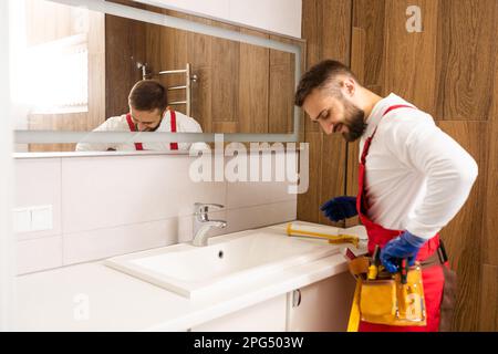 a worker installs a wash basin in a bathroom. Stock Photo