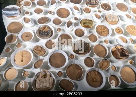 White porcelain bowls with yellow sand containing jewelry: rings, earrings, bracelets and baby bags with rhinestones. Stock Photo