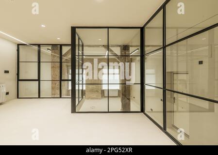 Modern loft apartment with vintage wooden beams and pillars, exposed brick walls, glass partitions with black metal frames, smooth white concrete floo Stock Photo