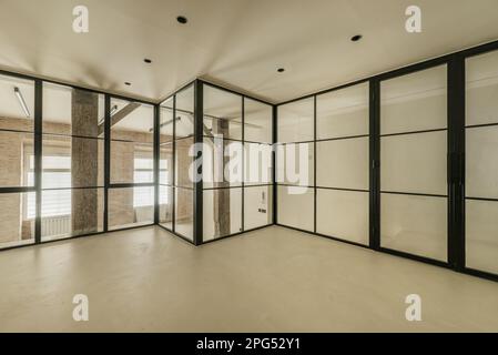 Modern loft apartment with vintage wooden beams and pillars, exposed brick walls, glass partitions with black metal frames, smooth white concrete floo Stock Photo