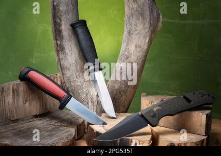 A set of various knives. Hunting and pocket knife. Several knives on the stump. Arrangement of knives on a tree. Variety of knives. Stock Photo