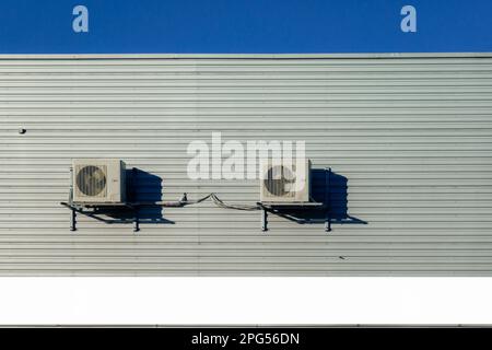 Two old air conditioner hangs on corrugated sheet metal wall of warehouse, storage, store. Industrial look. Outdoor Stock Photo