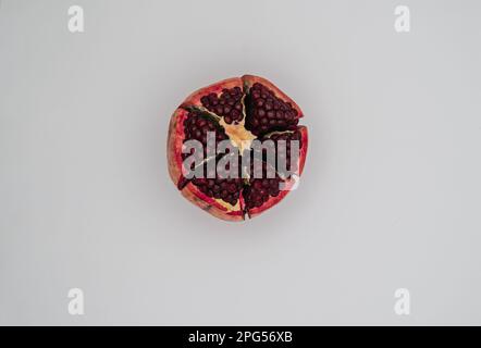 Top of view of half-peeled pomegranate. Close up and isolated on white background. Stock Photo