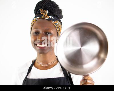 Young female chef showing  a stainless pan while smiling and looking at camera. Isolated on a white background Stock Photo