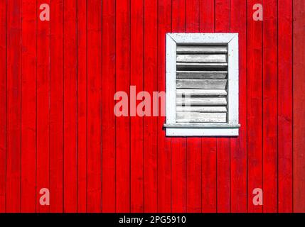Red wooden wall with white shuttered window on traditional Scandinavian building. Stock Photo