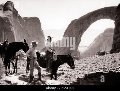 1930s TWO MEN LOOKING AT RAINBOW BRIDGE NATIONAL MONUMENT MAN STANDING WITH HORSE GUIDE ON HORSEBACK FIRST PUBLICIZED IN 1909 - m4350 HAR001 HARS UNITED STATES COPY SPACE FRIENDSHIP FULL-LENGTH PERSONS SCENIC INSPIRATION UNITED STATES OF AMERICA MALES WESTERN SERENITY SPIRITUALITY MONUMENT TRANSPORTATION B&W NORTH AMERICA COWBOYS FREEDOM NORTH AMERICAN RAINBOW HORSEBACK MAMMALS HIGH ANGLE ADVENTURE DISCOVERY WORLD'S EXCITEMENT PARKS TOURIST 1909 NATURAL OCCUPATIONS SOUTHERN CONNECTION GUIDE STYLISH HIGHEST SOUTHWEST NATIONAL PARK UTAH COOPERATION MAMMAL MID-ADULT MID-ADULT MAN Stock Photo