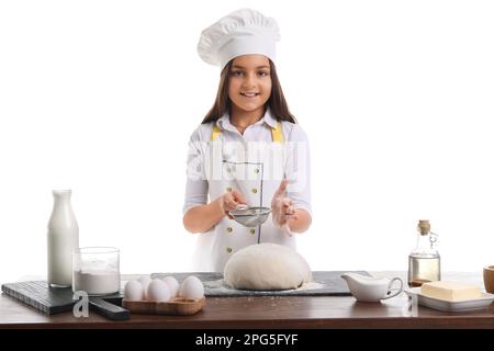 Little baker sprinkling flour onto dough on white background Stock Photo