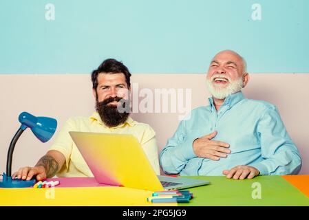Couple of two young office workers laugh looking at laptop screen. Happy diverse colleagues laugh watching funny content on computer. Stock Photo