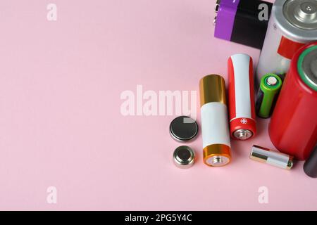 Different types of batteries on pink background, closeup. Space for text Stock Photo