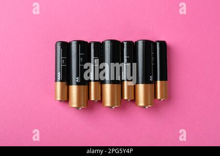 Many different batteries on pink background, flat lay Stock Photo