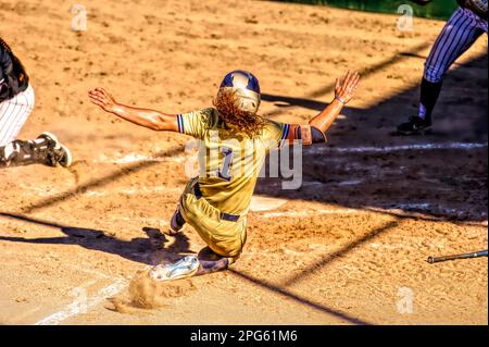 A Female Softball Player Is Sliding Into Home Plate Stock Photo