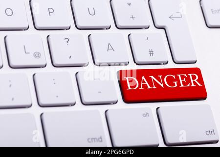 Alluminium keyboard with DANGER word written on red button close up photo Stock Photo