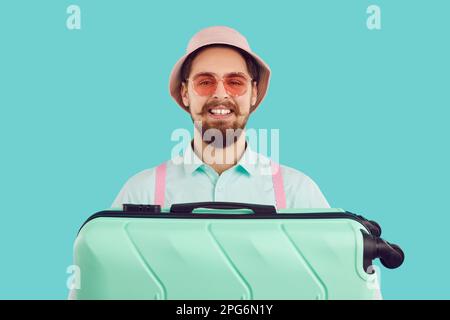 Happy young male tourist in hat and sunglasses holding his travel blag and smiling Stock Photo