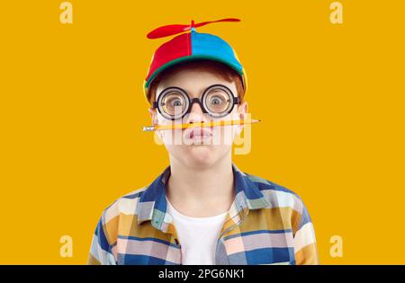 Studio portrait of funny preteen boy who is fooling around holding pencil as mustache. Stock Photo