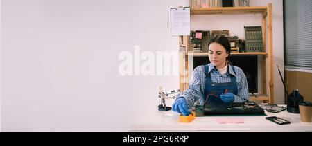 Technician repairing computer hardware in the lab. Engineer checking motherboard with multimeter. Computer diagnostic, maintenance support and Stock Photo